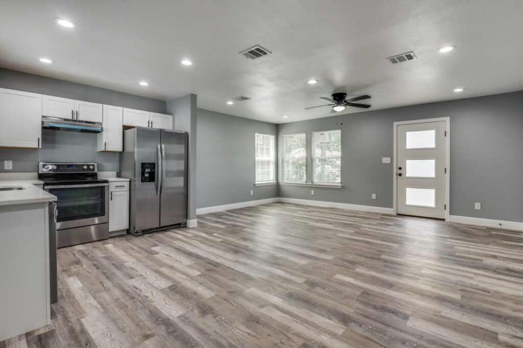 Renovated open kitchen and living area with new flooring and stainless steel appliances